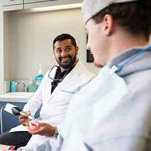 Smiling dentist showing patient digital impressions of teeth
