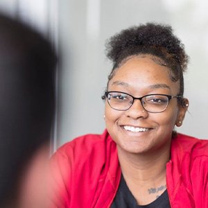 Woman in red shirt and black framed glasses smiling