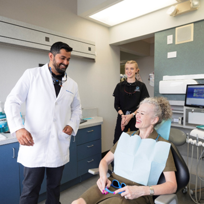 Dr. Shroff and a dental hygienist speaking with a patient