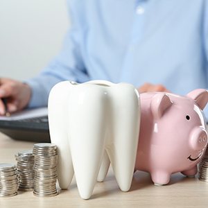 Coins and tooth next to a piggy bank