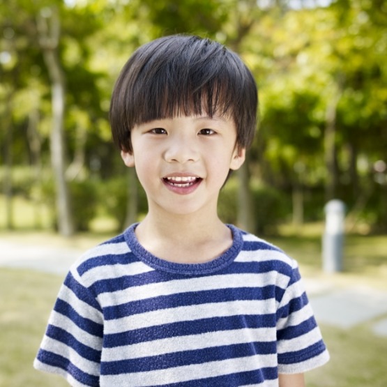 Little boy in striped shirt smiling outside