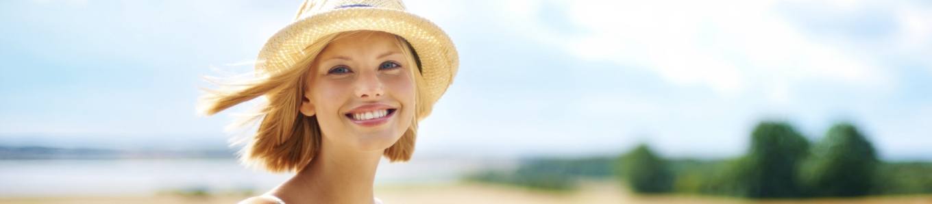 Woman in straw hat smiling after cosmetic dentistry in Centennial