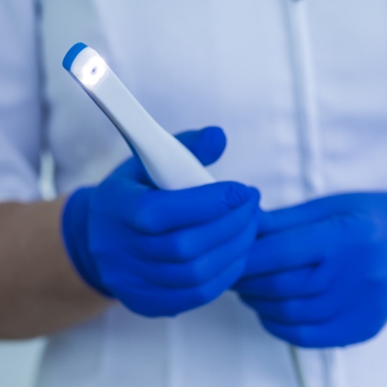 Blue gloved hands holding an intraoral camera