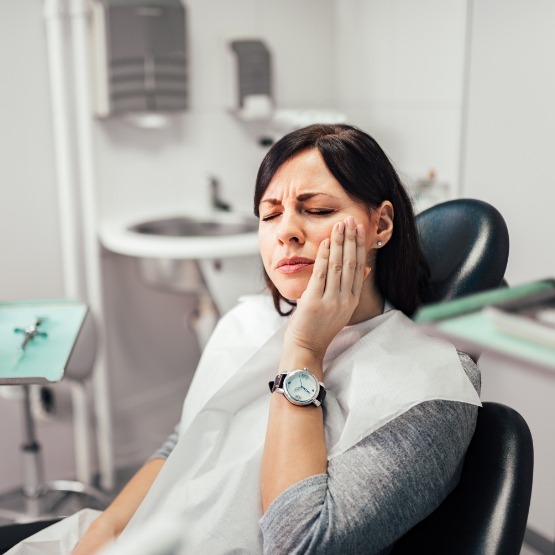Female dental patient rubbing cheek in pain