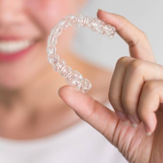 Woman holding an aligner for Invisalign
