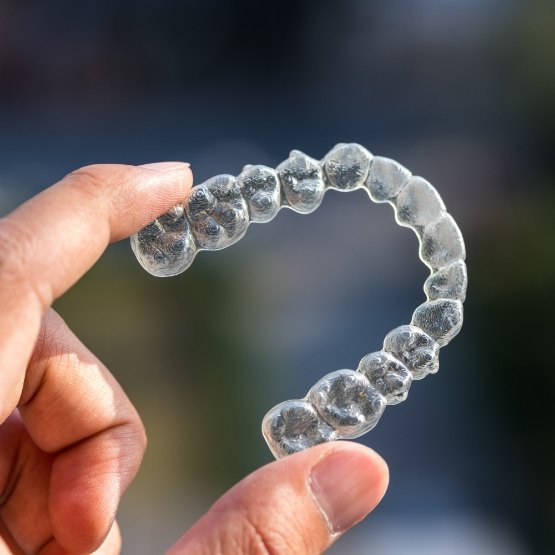 Close up of hand holding an Invisalign aligner