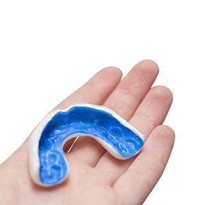 Patient holding blue and white mouthguard