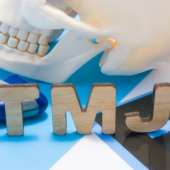 Letters spelling out TMJ next to model of skull
