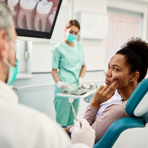 Woman with toothache looking at dentist in treatment chair