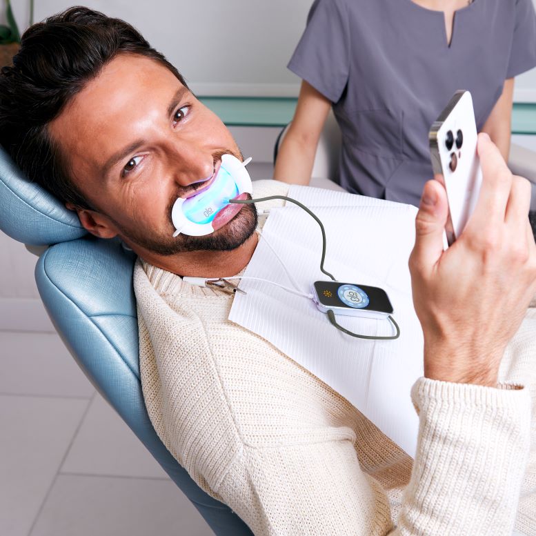Man looking at phone during teeth whitening treatment
