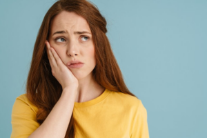 Woman holding her jaw and looking concerned